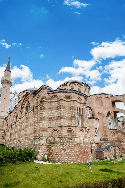 Tall view of the rounded east end of a brick church with a dome above and a minaret at the left edge