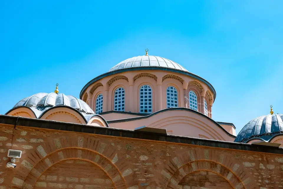 Lead-covered domes on windowed drums topped with gilded crescents, seen above a brick wall