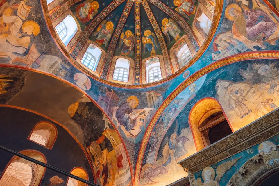 Frescoed dome with angels painted between its ribs and writing figures seated at desks in the corners below